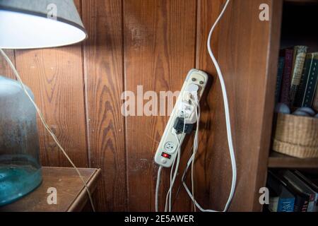 A surge protector with many cords plugged in is mounted on the wall. Stock Photo