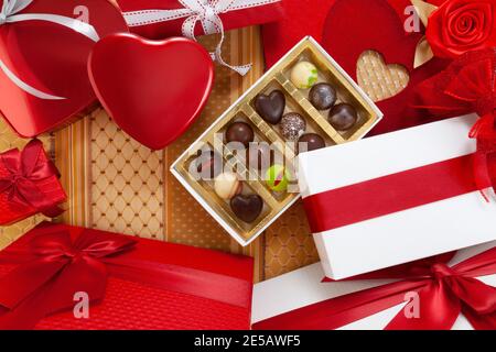Valentines day background, composition of gift boxes chocolates and red heart metal shaped boxes, with bows and ribbons, top view on ornamental fabric Stock Photo