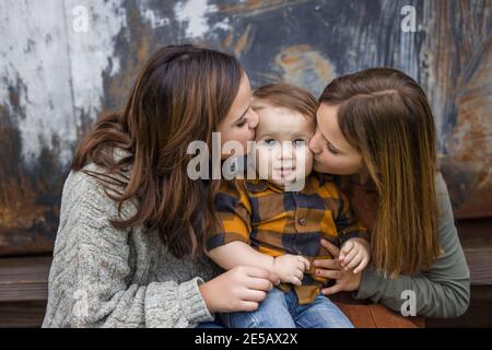 Two sisters and a little baby brother sitting on steps outside for a portrait Stock Photo