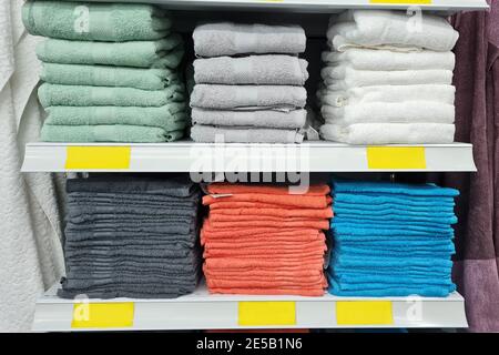 Stacks of beautiful white, brown, blue, green and gray towels of pastel colors sells on a showcase in the store. Empty yellow blanks for prices. Scand Stock Photo