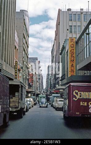 A busy Little Collins Street, Melbourne, Victoria, Australia in 1961, in the city’s central business district. The narrow street runs parallel to and to the north of Collins Street. Here deliveries are being made. Signs for businesses include Frank Sedgeman’s Gym, a Bank of NSW, Rockmans and a billiard hall. Francis ‘Frank’ Sedgman (b. 1927) was an Australian tennis player whose career ran from 1945 until 1976. Sedgman won five Grand Slam singles tournaments as an amateur as well as 22 Grand Slam doubles titles. Today this street has many boutique shops and bars in the lanes running off it. Stock Photo