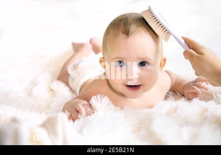 The mother is combing the little baby's hair. Selective focus. People. Stock Photo