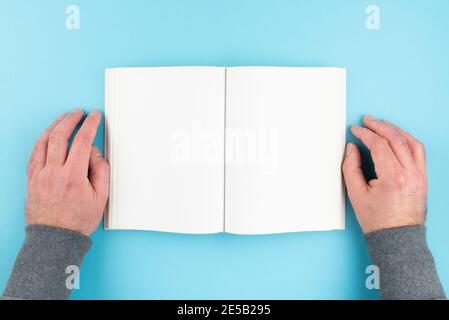 overhead view of person reading book with hands resting on both sides, blank page hardcover book with copy space Stock Photo