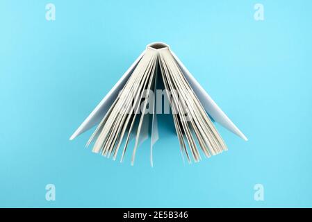 directly above view of top of open hardcover book on blue background Stock Photo