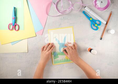 DIY and kids creativity. Step by step instruction: how to make card Happy easter. Step5 glue flower instead of rabbit tail. Childrens handmade Easter Stock Photo