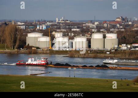 Duisburg, Ruhr area, North Rhine-Westphalia, Germany - Duisburg ports, strollers on the Rheinhausen meadows, cargo ship on the Rhine, tank farm of Oil Stock Photo