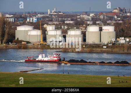 Duisburg, Ruhr area, North Rhine-Westphalia, Germany - Duisburg ports, strollers on the Rheinhausen meadows, cargo ship on the Rhine, tank farm of Oil Stock Photo