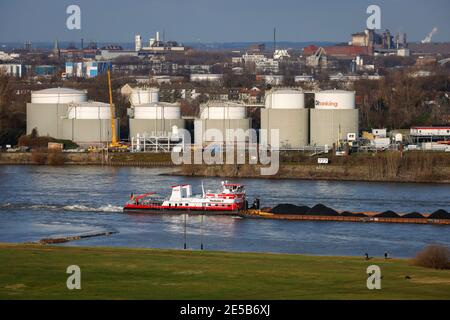 Duisburg, Ruhr area, North Rhine-Westphalia, Germany - Duisburg ports, strollers on the Rheinhausen meadows, cargo ship on the Rhine, tank farm of Oil Stock Photo