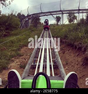 Man Riding at Bobsled Roller Coaster Rail Track in Summer Fun Park