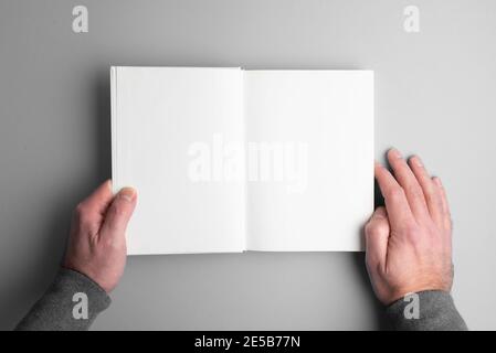 overhead view of person opening blank page hardcover book on gray desk surface Stock Photo