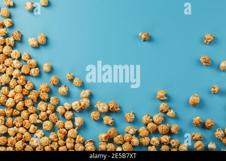 Popcorn is scattered on a blue background, in the form of a frame. Yummy for the filming of movies, TV series, cartoons. Free space, top view Stock Photo