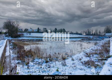 Frozen village pond in winter of 2021, Hawkesbury Upton, The Cotswolds, Gloucestershire, England, UK