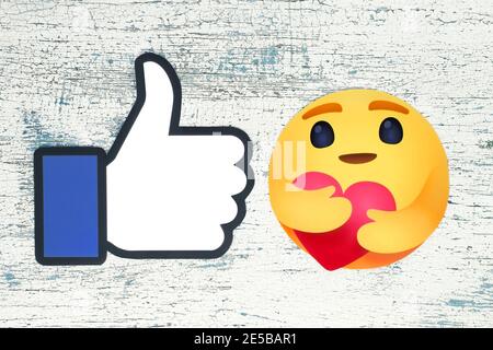 Kiev, Ukraine - August 25, 2020: Facebook new Care Empathetic Emoji Reaction and Facebook Like on wooden background. Facebook is adding a hug reaction Stock Photo