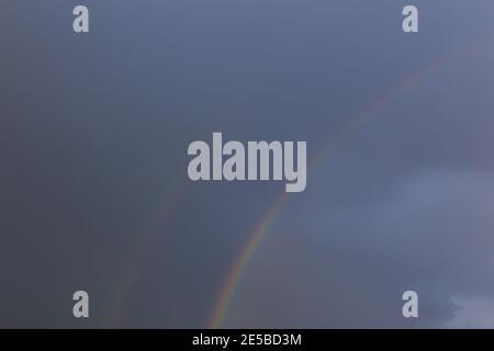 Dark sky with double rainbow, one fading out Stock Photo