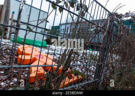 Freiburg, Germany. 27th Jan, 2021. An orange plastic display lies behind a fence in the play area of the Immergrün daycare centre, while the building of the facility can be seen in the background. According to the Diakonie Baden, 14 teachers and 10 children of the day-care centre Immergrün in Freiburg are suspected to be infected with a mutated variant of the corona virus. (to dpa: '24 suspected cases of corona mutant in Freiburg day-care centre') Credit: Philipp von Ditfurth/dpa/Alamy Live News Stock Photo