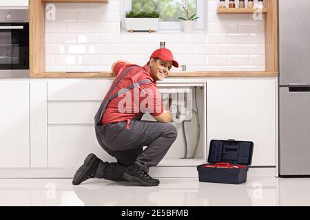 Plumber repairing a pipe under sink in a modern kitchen Stock Photo