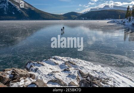 Two ice skaters on Lake Minnewanka in Banff National Park, Alberta, Canada Stock Photo