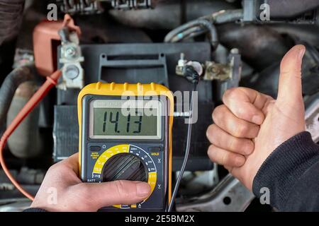 Checking car battery and alternator voltage with running engine Stock Photo