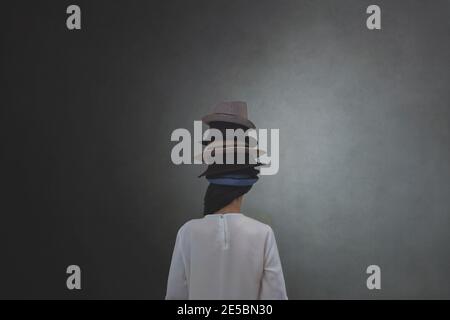 woman from behind wears countless hats on her head, concept of multiple personalities and identities Stock Photo