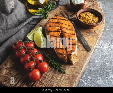 grilled steak fish salmon, trout in a old wood board, spices, rosemary, tomato, Stock Photo