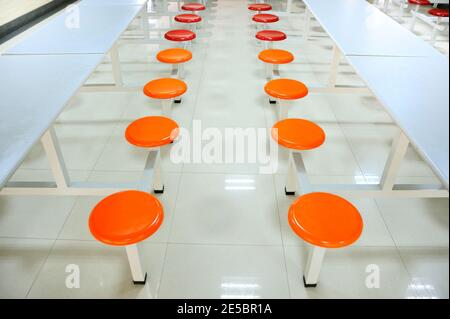 Rows of orange plastics seats in empty school canteen Stock Photo