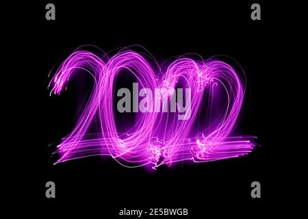 Long exposure photography. Writes 2022 with pink light on black background. New year 2022 concept. Neon lights wallpaper.