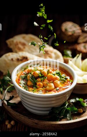 Traditional hummus with the addition of olive oil, paprika powder and chickpeas sprinkled with fresh chopped parsley close-up Stock Photo