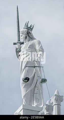 Ancient statue of goddess Justice with sword and scale at the roof top decoration of Doge's Palace in Venice, Italy, closeup Stock Photo