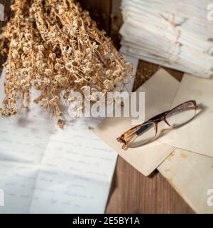Open handwritten letter and Pile of Old Letters in envelopes, eyeglasses and a dry bouquet of flowers. Nostalgia and memories concept Stock Photo