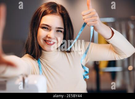 Young dressmaker woman taking selfie. Seamstress in workshop Stock Photo