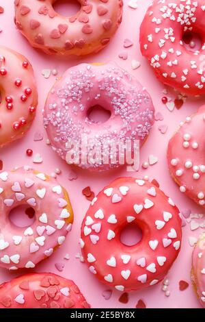Valentine's donuts with icing and sugar sprinkles on a pink background top view Stock Photo
