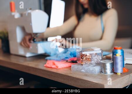 Close up young dressmaker woman working on sewing machine. Creating online clothing design courses. Stock Photo