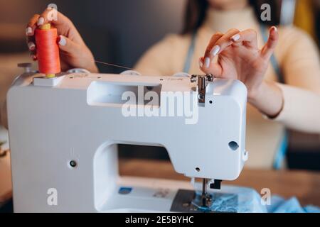 Close up young dressmaker woman with sewing machine. Creating online clothing design courses. Stock Photo