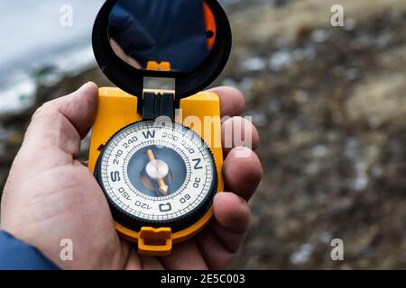Compass in hand. Navigation on the terrain using a magnetic compass. Stock Photo
