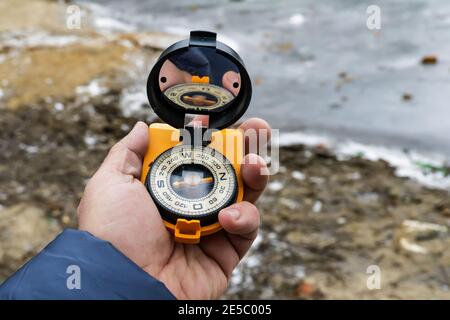 Compass in hand. Navigation on the terrain using a magnetic compass. Stock Photo
