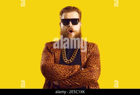 Eccentric bearded man in leopard print jacket with gold neck chain standing arms crossed Stock Photo