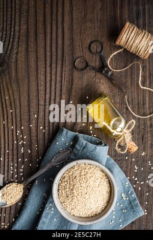 Healthy cold pressed sesame oil in a glass bottle and seeds in a bowl on wooden background Stock Photo