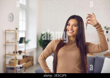 Happy young woman holding keys to her new house or apartment and smiling at camera Stock Photo