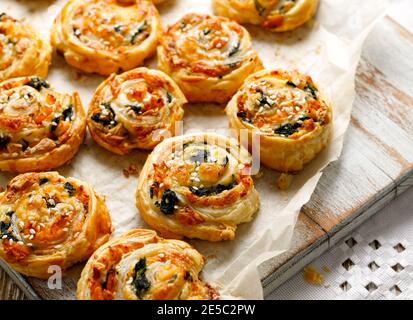 French Puff Pastry Pinwheels stuffed with salmon, cheese and spinach on on baking paper, close up view Stock Photo