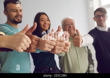 Group of positive diverse people celebrating successful teamwork and showing thumbs-up Stock Photo
