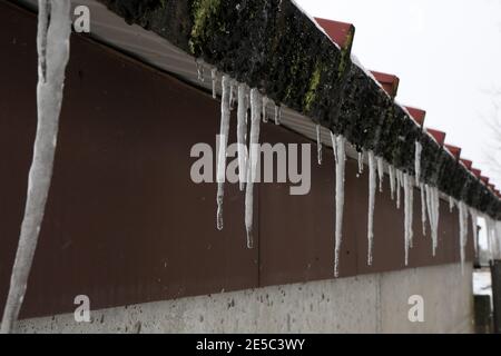 The snow on the roof melts and forms ice icicles. Stock Photo