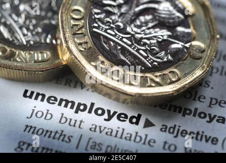 DICTIONARY DEFINITION OF WORD UNEMPLOYED WITH ONE POUND COINS RE COVID 19 CORONAVIRUS WORKERS FURLOUGHED FURLOUGH ETC UK Stock Photo
