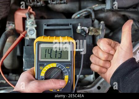 Checking car battery and alternator voltage with running engine Stock Photo