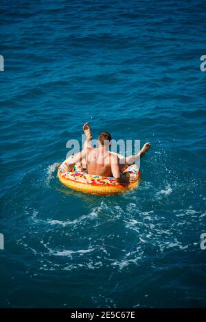 A man floats on an inflatable ring in the sea with blue water. Vacation at the sea on a sunny day. Turkey vacation concept Stock Photo