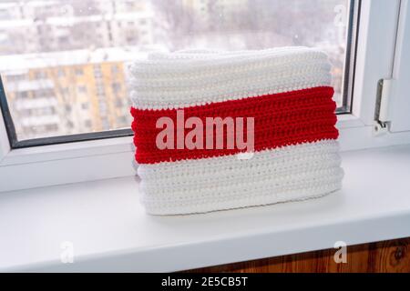 Knitted scarf white red white lies on windowsill Stock Photo