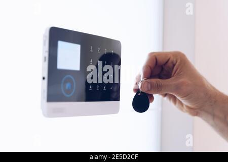 The hand with the remote control disarms the security system. Stock Photo