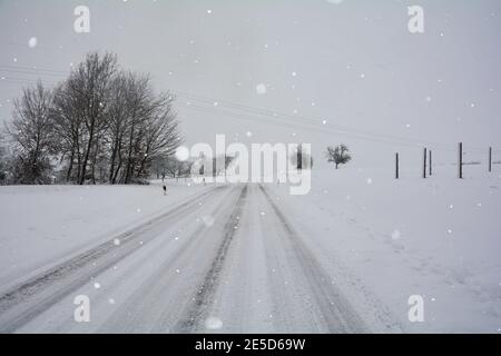White country road in winter with a lot of snow and snowfall, in Bavaria, Germany Stock Photo