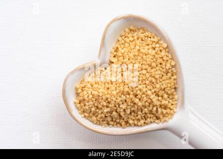 Uncooked French Couscous on a Heart Shaped Spoon Stock Photo