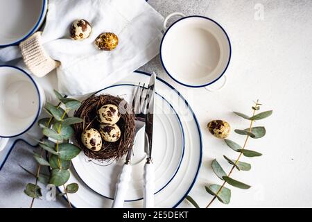 Easter table setting with Easter eggs in a bird's nest and eucalyptus stems Stock Photo