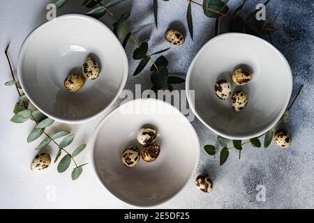Easter table setting with bowls of Easter eggs and eucalyptus stems Stock Photo